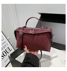 Détail d'un sac à main bordeaux en cuir avec fermetures éclair et poignée ronde