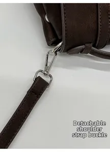Macro detail of the silver spring swivel hook and textured brown leather bag strap