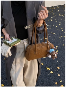 Détail du sac Boston en daim marron avec surpiqûres et un joli pendentif d'ours bleu
