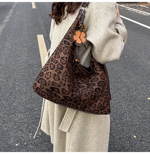 Detailed close-up of a leopard print tote bag with a unique floral and wooden bead charm