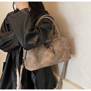 Dettaglio della borsa Boston vintage con catena a croce in metallo e lucchetto su modella