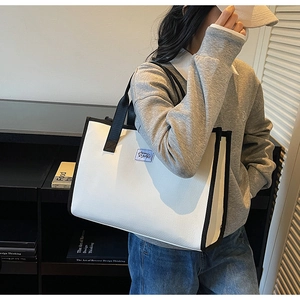 Gros plan détaillé d'un grand sac cabas à carreaux avec garniture en cuir noir et logo tissé