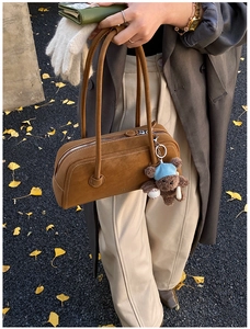 Détail d'un sac Boston en daim marron avec longues anses et breloque ourson
