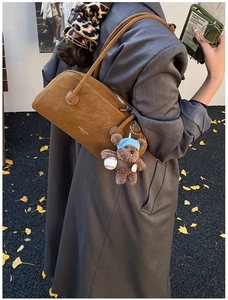 Détail rapproché du sac à main en daim marron avec logo NIIDEE et charmant ours en peluche