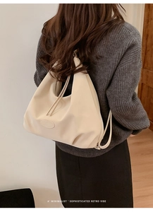 Rückansicht eines Models mit einer cremeweißen großen Hobo-Tasche mit weicher Faltung