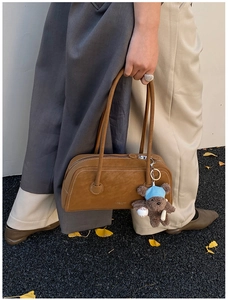 Détail du sac Boston vintage en daim marron avec surpiqûres et un charme d'ours