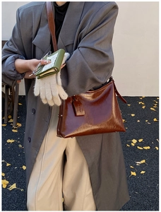 Brown glossy leather shoulder bag shown against a minimalist autumn street backdrop