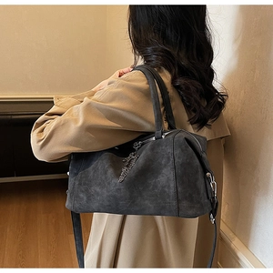 Borsa a tracolla grigio scuro con catena vista da dietro su un cappotto beige