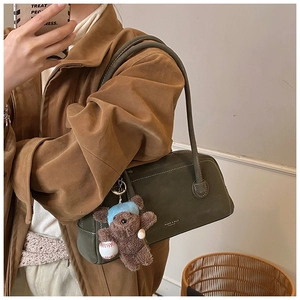 Détail du sac en cuir mat vert foncé avec fines bretelles et pendentif ours