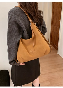 Detail of caramel leather hobo tote with elegant tassels and oval brand emblem