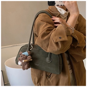 Détail du sac seau vintage en daim vert olive avec logo blanc et breloque ours en peluche