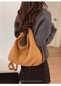 Rückansicht des Models mit minimalistischem Lederrucksack in Karamell in warmem Raum