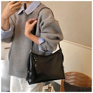 Detail of glossy patent leather tote bag featuring adjustable strap and side rivet accents