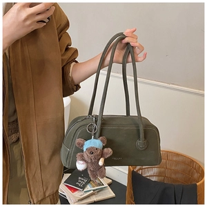 Détail du sac Boston vert olive avec surpiqûres blanches et pendentif ours en peluche