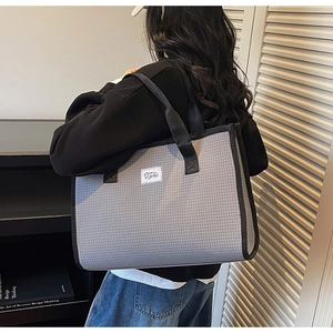 Détail d'un grand sac cabas à carreaux gris avec anses noires dans un décor moderne