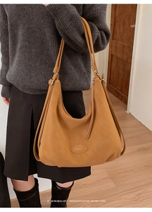 Detail of ginger leather tote bag with embossed fashion logo and side ribbon accent