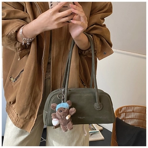 Détail d'un sac Boston vintage en daim vert foncé avec un charmant ours marron