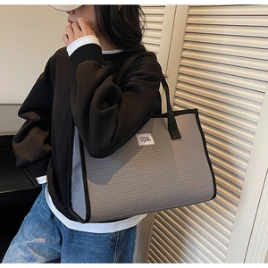 Détail du sac cabas à carreaux gris avec anses noires et étiquette logo blanche