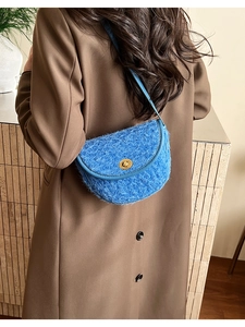 Detailansicht einer blauen, flauschigen Retro-Satteltasche über einem braunen Mantel