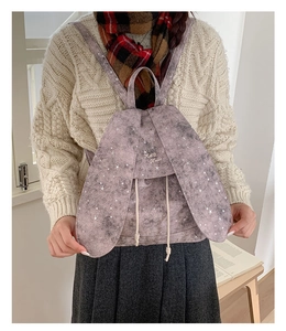 Detail showing plush rabbit ears and white star patterns on the dusty pink canvas backpack