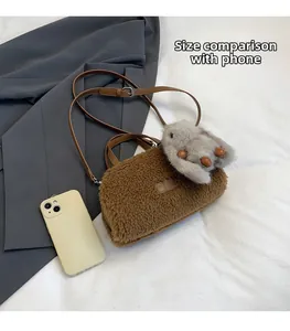 Detail of faux shearling crossbody bag with a rabbit charm and size comparison to a phone