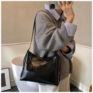 Model wearing a large black glossy leather tote bag for everyday commuting style