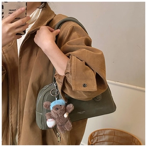 Détail du sac à main en daim vert foncé avec pendentif ours et coutures de qualité