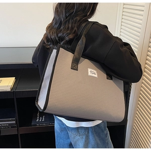 Détail du grand sac cabas à carreaux avec bordure noire porté par un modèle