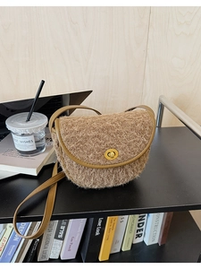 Detailansicht der braunen Plüsch-Satteltasche mit Goldschnalle auf Holzregal