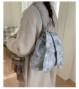 Gray star print backpack with cute rabbit ear flap and drawstring closure on model