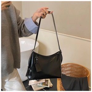 Detail of minimalist black faux leather shoulder bag worn with casual autumn outfit