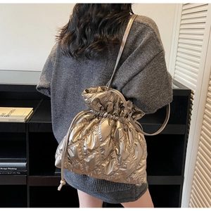 Close-up of champagne gold quilted bucket bag with drawstring and metallic finish