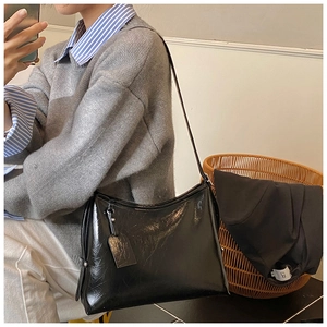 Close-up of a glossy black leather bucket bag featuring a sleek finish and shoulder strap