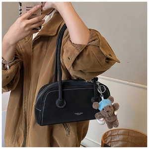 Détail du sac bowling rétro noir avec surpiqûres contrastées et pendentif d'ourson