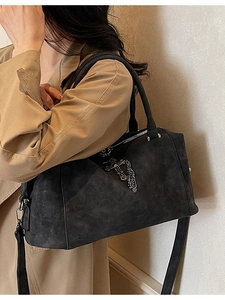 Borsa Boston nera opaca con catena a croce argento indossata da modella in trench coat