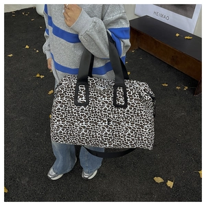 Dettaglio di una grande borsa da viaggio leopardata con cinghie nere e tessuto resistente