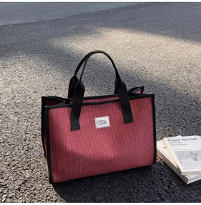 Détail du cabas en toile à carreaux rouges avec anses noires et étiquette Mummy Bags