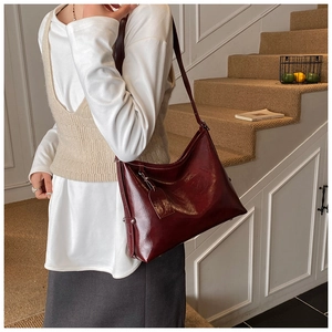 Detailed close-up of dark red oil wax leather shoulder bag with metallic rivets and strap