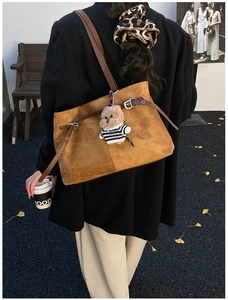 Détail du sac fourre-tout en daim marron avec lanières en cuir et charm ours en peluche