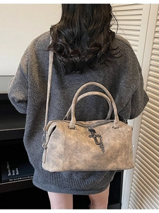 Borsa Boston grigia in pelle vintage con pendente a croce mostrata in un set lifestyle