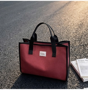 Détail du grand sac cabas en toile à carreaux rouges avec poignées noires et étiquette