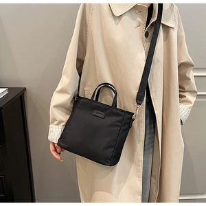 Detail of black tote bag with CLEAR metal plaque and adjustable wide shoulder strap