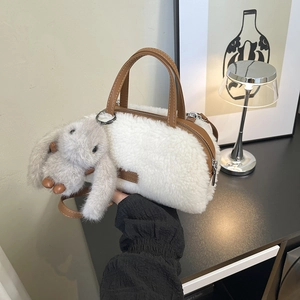 Detail der cremefarbenen Plüsch-Beuteltasche mit braunen Ledergriffen und Hasenanhänger