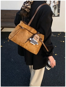 Dettaglio di una grande borsa tote in pelle scamosciata marrone con ciondolo a orsetto