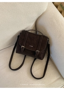 Dettaglio dello zaino vintage in pelle marrone caffè con fibbie su un divano