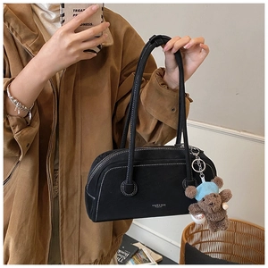 Détail d'un sac Boston vintage avec coutures contrastées et un charmant ours en peluche