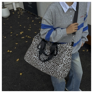 Dettaglio della borsa tote in tela leopardata con tracolla larga indossata da modella