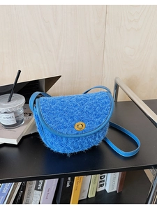 Blaue Woll-Satteltasche mit Goldverschluss auf einem Schreibtisch mit Kaffee und Büchern