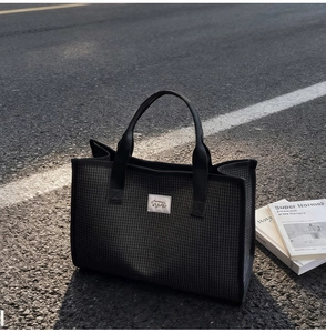 Détail d'un sac cabas à carreaux avec texture tissée sur pavé sous la lumière naturelle
