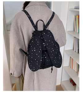 Detail of black star-print backpack featuring cute bunny ears on the top cover